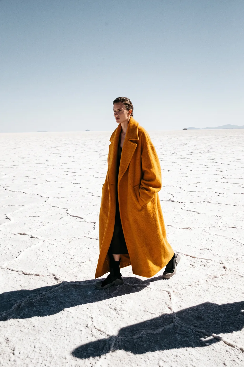 Model in an oversized saffron coat walking across a white salt flat – Nano Banana 2.1 example, 2:3